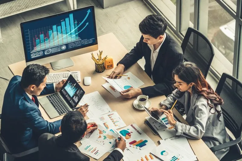 A commercial team reviewing sales dashboards on a wall of monitors.